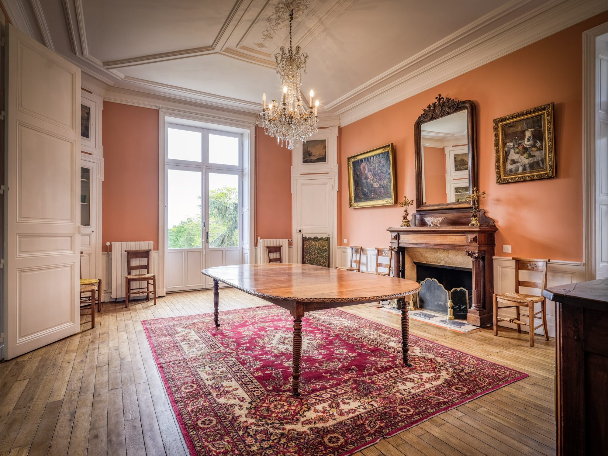 La salle à manger aux murs corail et sa grande table